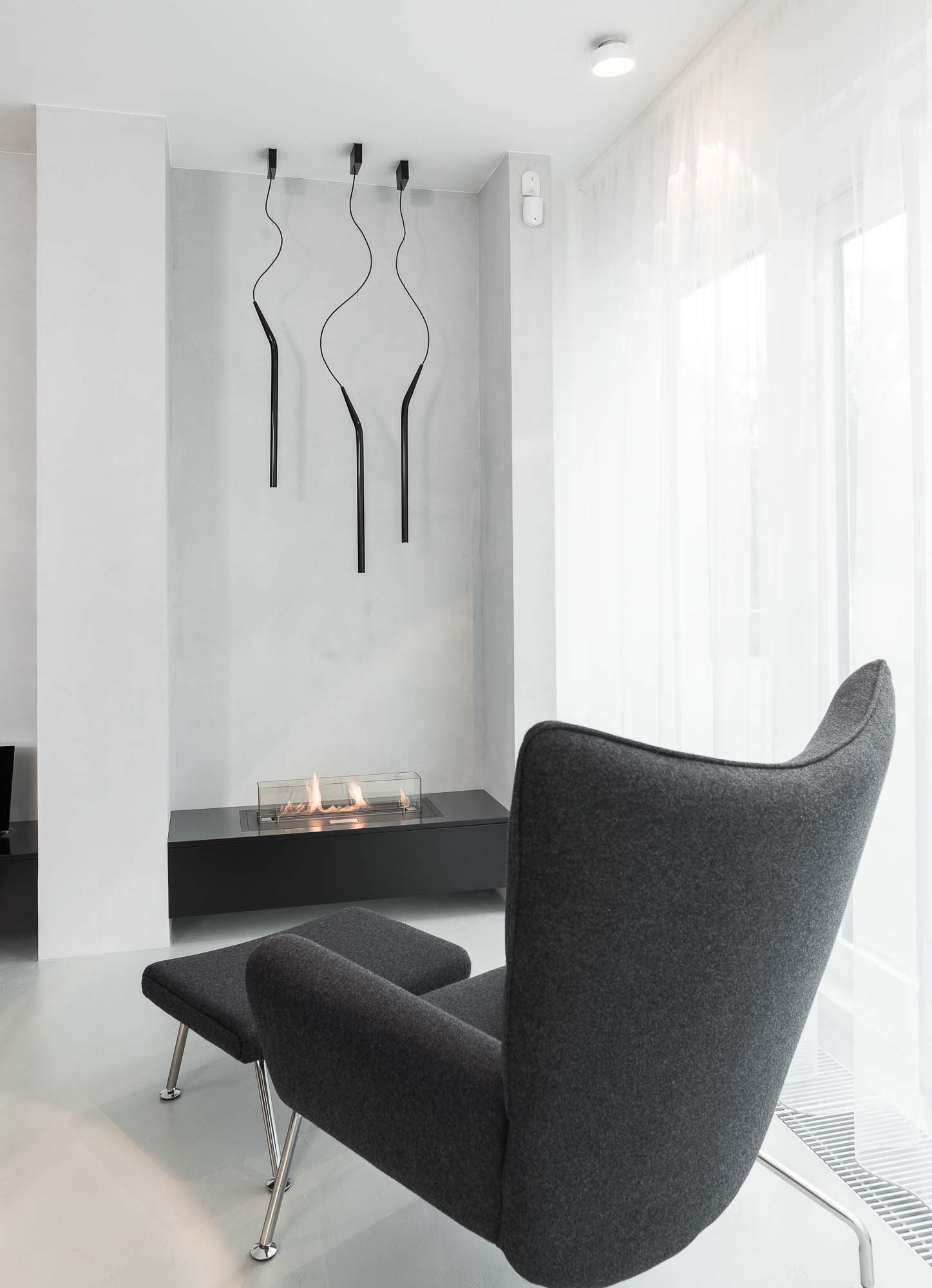 Čtecí koutek s designovým křeslem a designovým svítidlem v minimalistickém interiéru od OOOOX