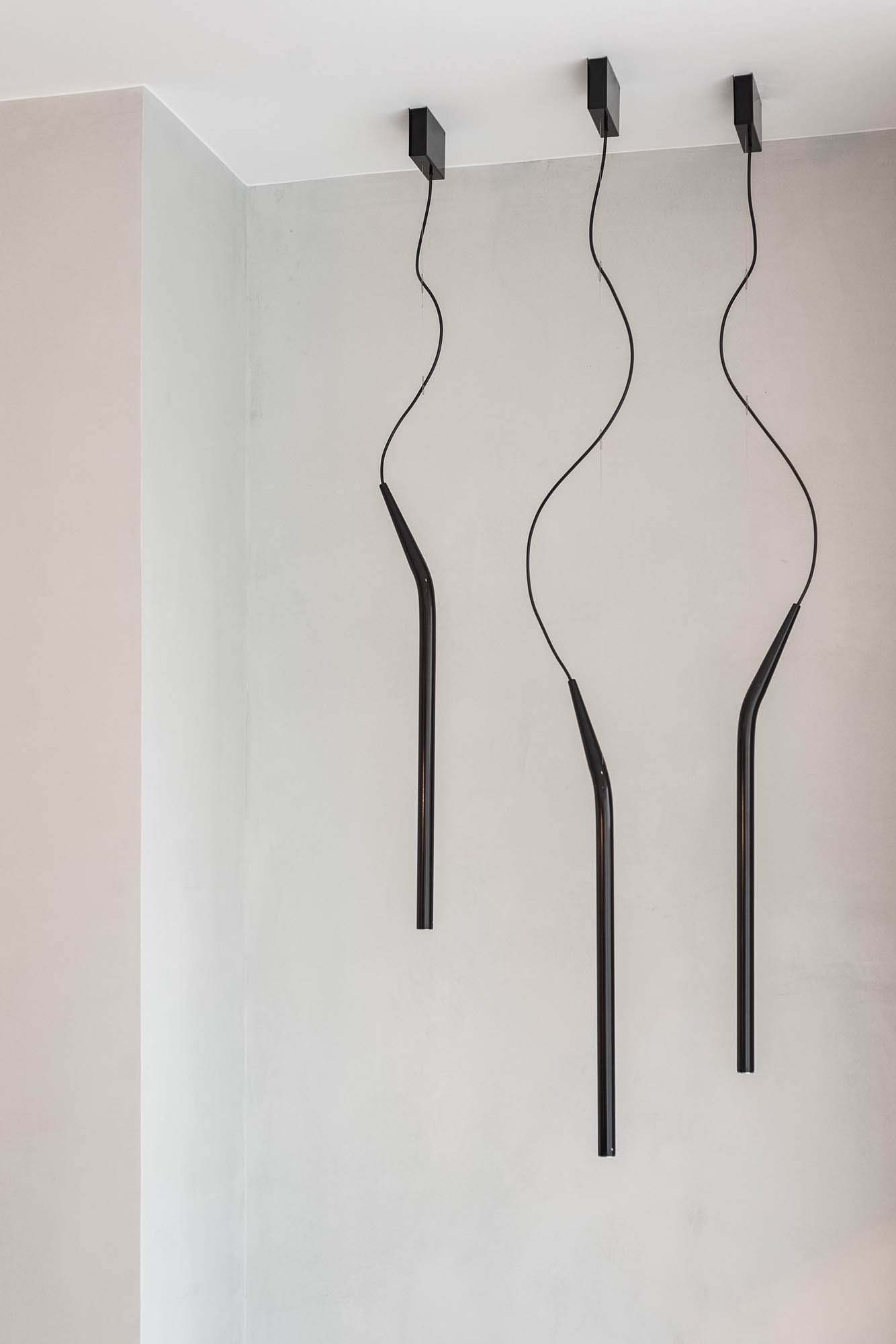 Detail designového svítidla v minimalistickém interiéru od OOOOX