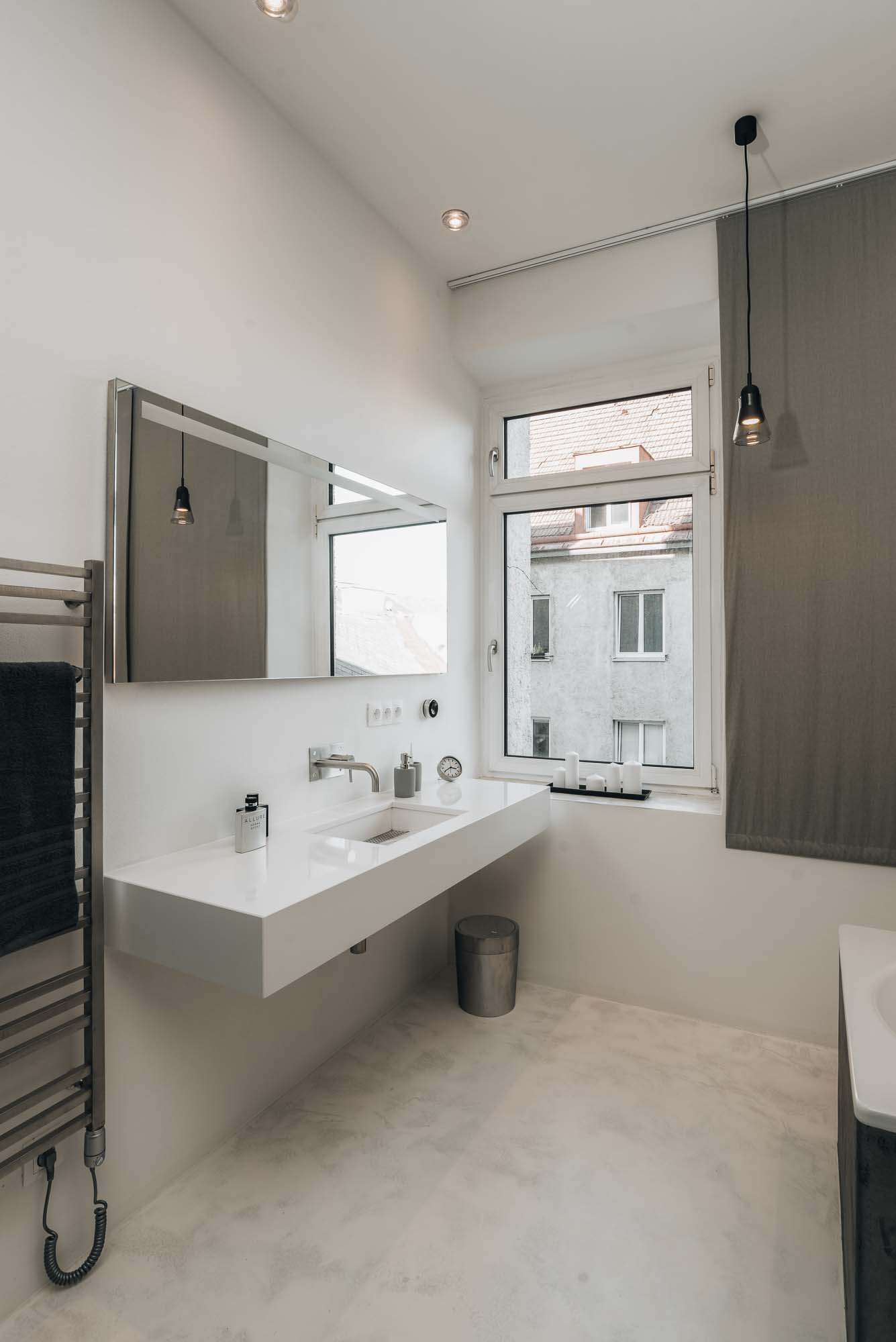 Koupelna s volně stojící vanou, betonovou stěrkou na podlaze, minimalistickou umyvadlovou deskou a syrovými povrchy v industriálním loftovém interiéru. Design by OOOOX
