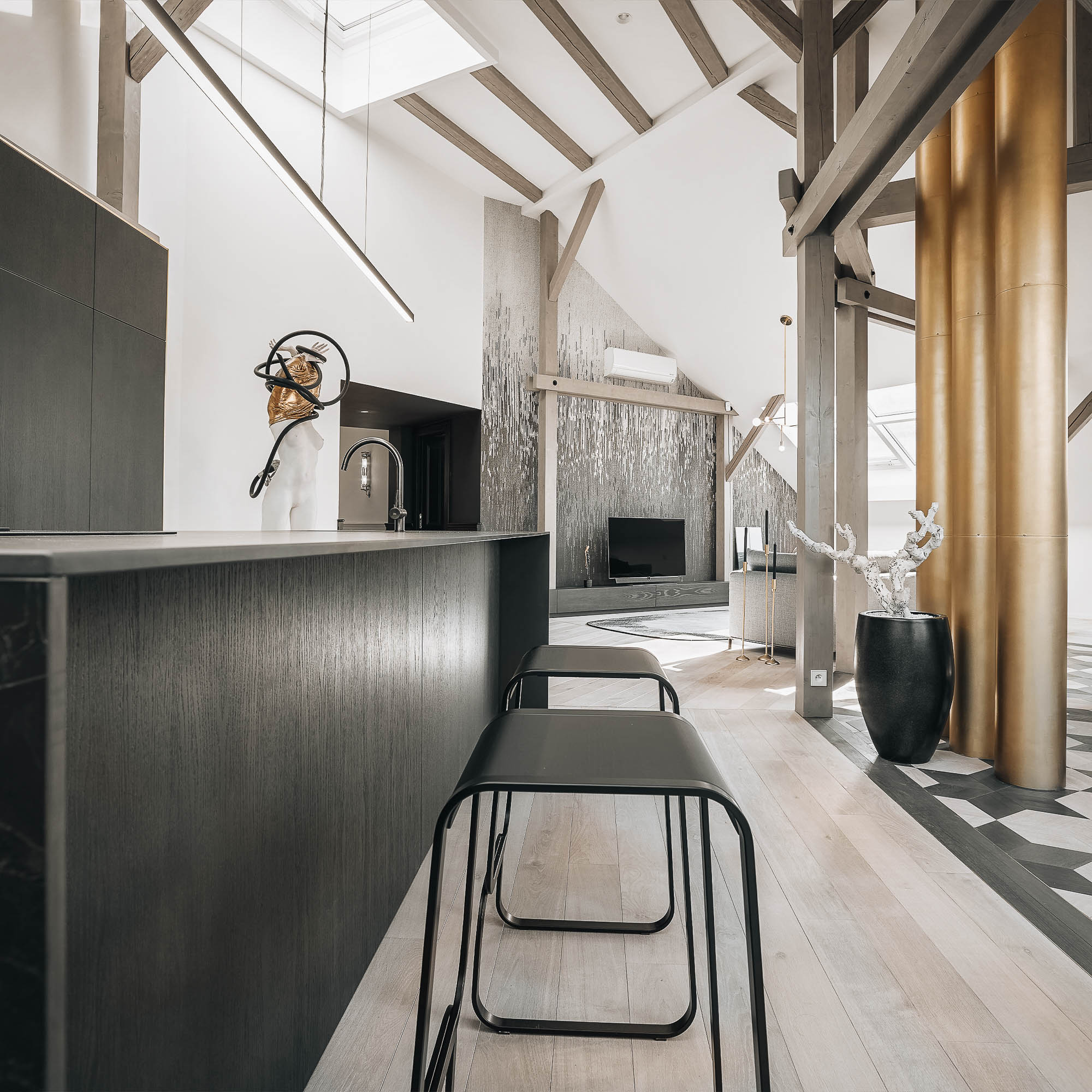 Detail of a kitchen island in black veneer, delicate bar stool and open space with brass chimneys in the Josefov reconstruction interior | design by OOOOX