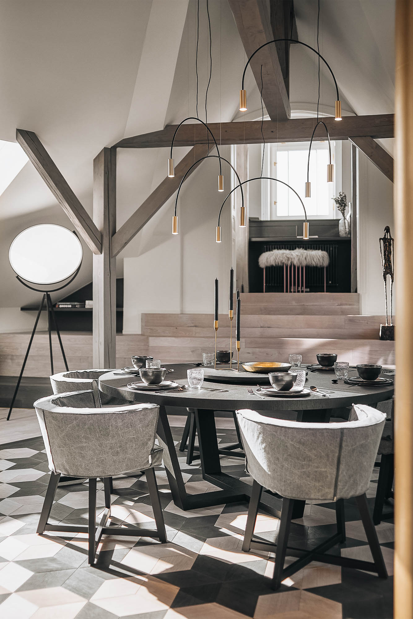 Circular dining table with upholstered chairs and original chimneys in a golden tone as the dominant feature – Josefov attic apartment reconstruction by OOOOX