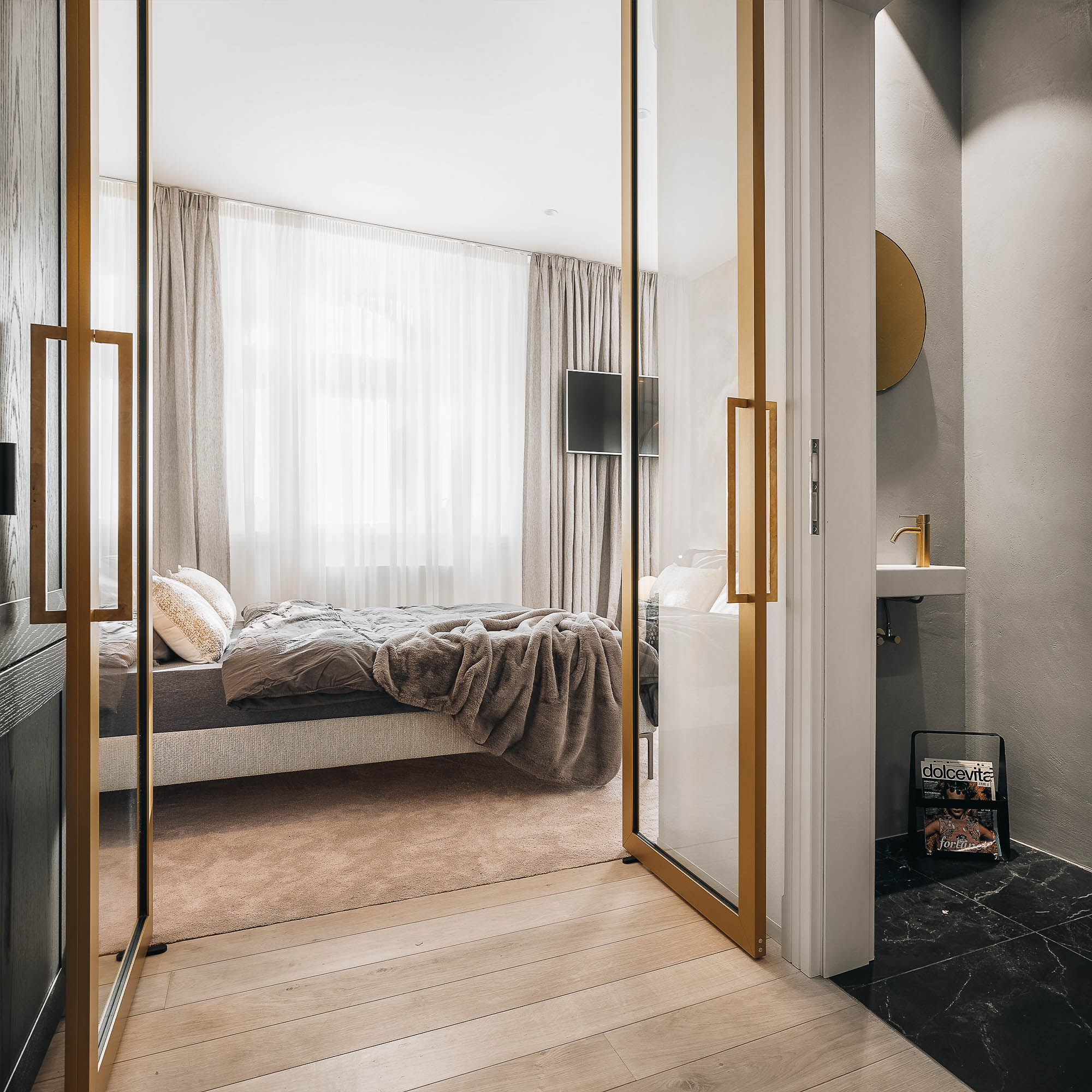 View through glazed wardrobe doors into the bedroom area of the attic apartment | design by OOOOX