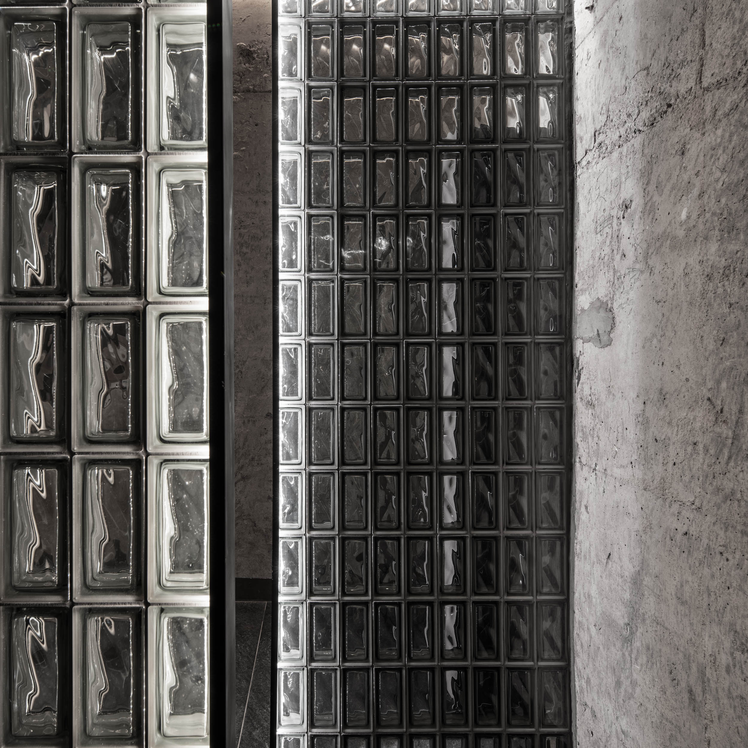 VANGUARD wellness glass block partition detail — illuminated light and dark glass blocks, raw concrete wall in contrast, industrial design | OOOOX