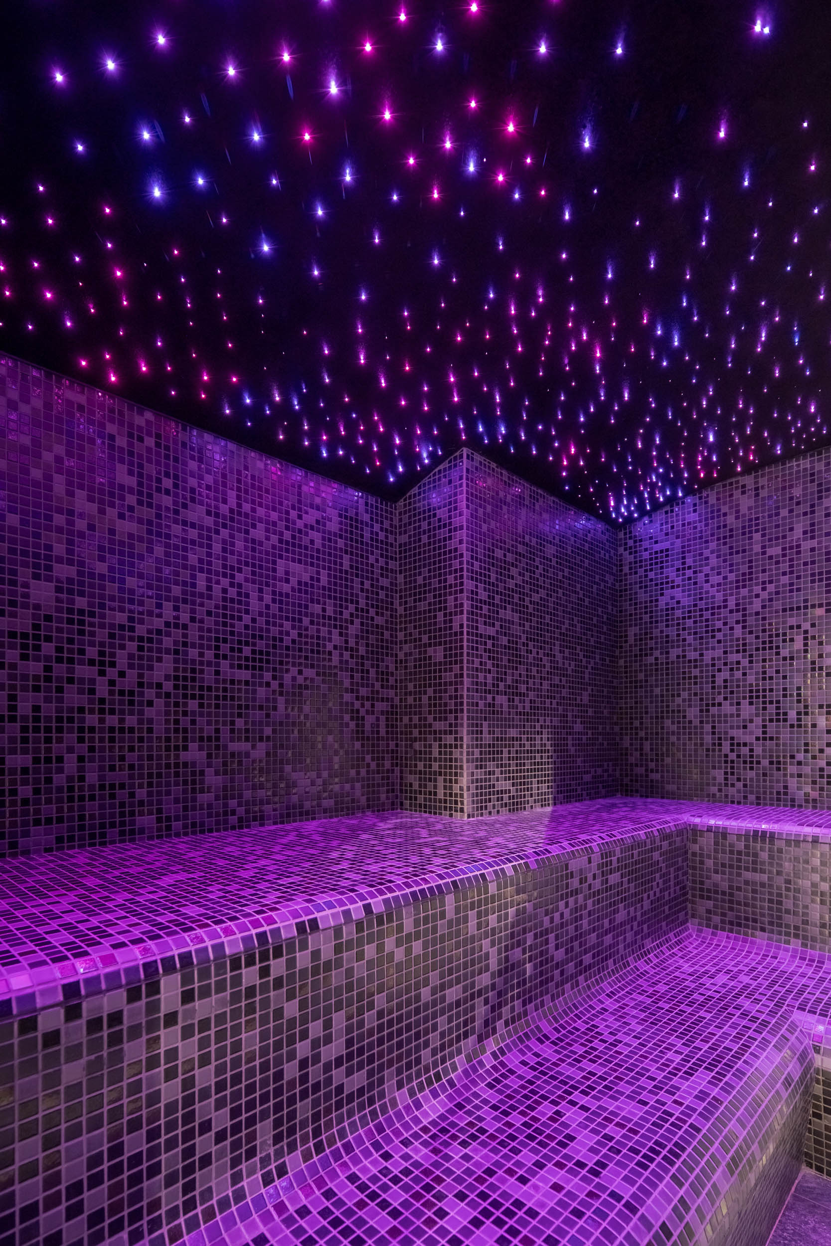 VANGUARD wellness steam room — fibre-optic ceiling simulating starry sky, purple LED-lit mosaic tiled benches, intimate atmosphere | OOOOX
