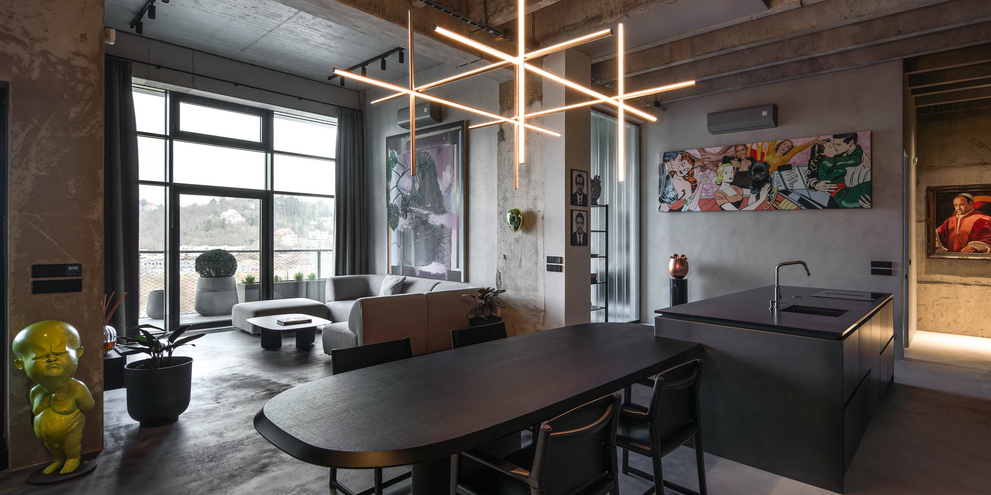Detail napojení oválného černého jídelního stolu na kuchyňský ostrůvek v minimalistickém industriálním interiéru s designovým závěsným svítidlem. Design by OOOOX