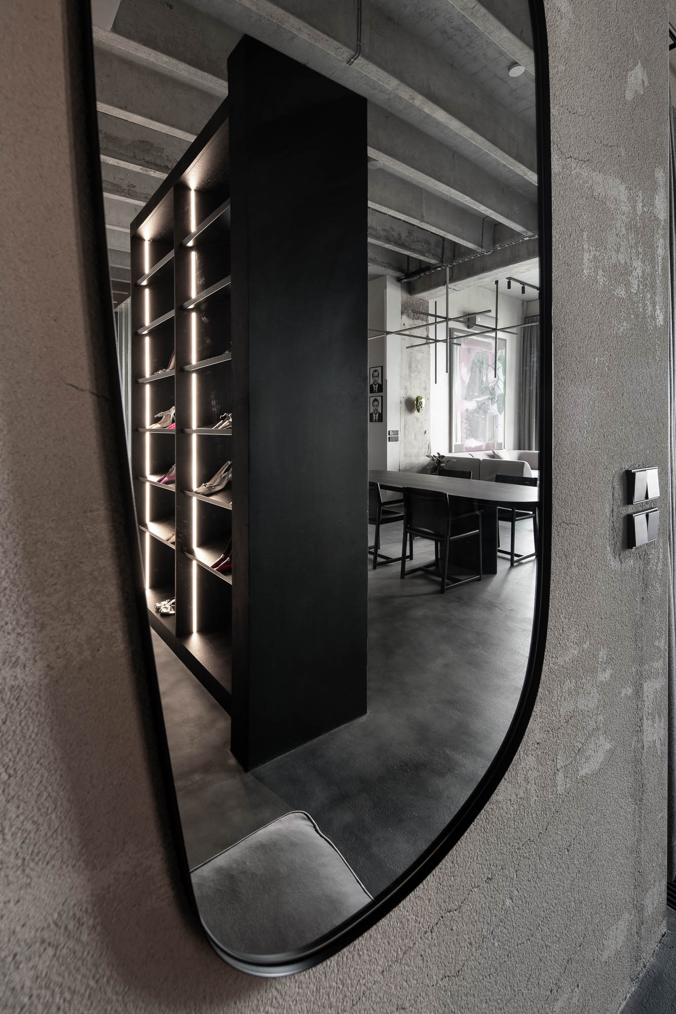 Pohled na vestavěnou šatní skříň a otevřený prostor loftu Vanguard se syrovými betonovými povrchy a minimalistickým interiérem. Design by OOOOX