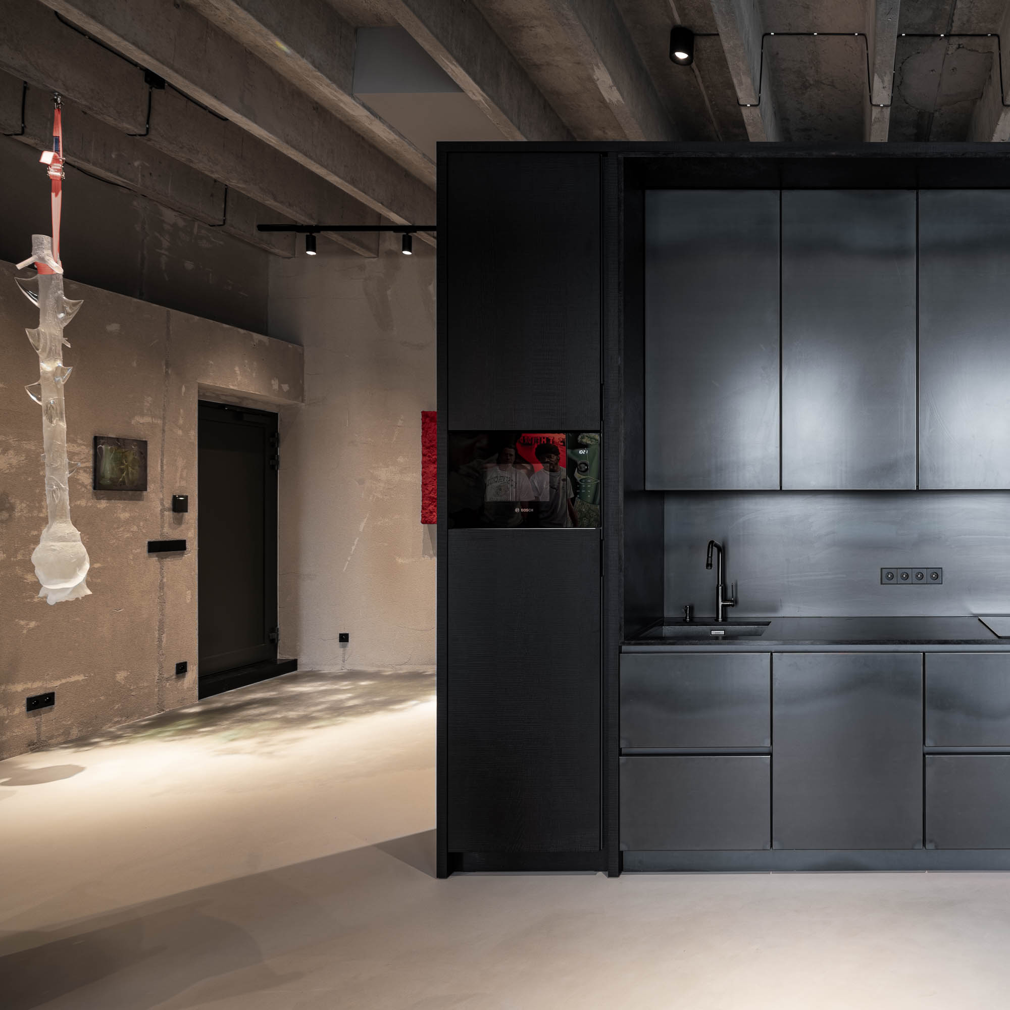 Černá matná kuchyň integrovaná do nábytkového bloku loftového bytu Vanguard s přiznanou průmyslovou architekturou a zavěšenou skleněnou sochařskou instalací – OOOOX
