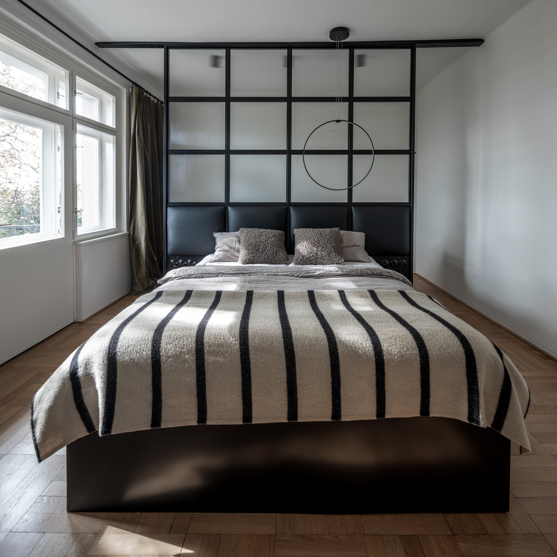 Pohled na ložnici s okny do zahrady, původní parketová podlaha ve vzoru rybí kosti, vzdušný minimalistický interiér. OOOOX
