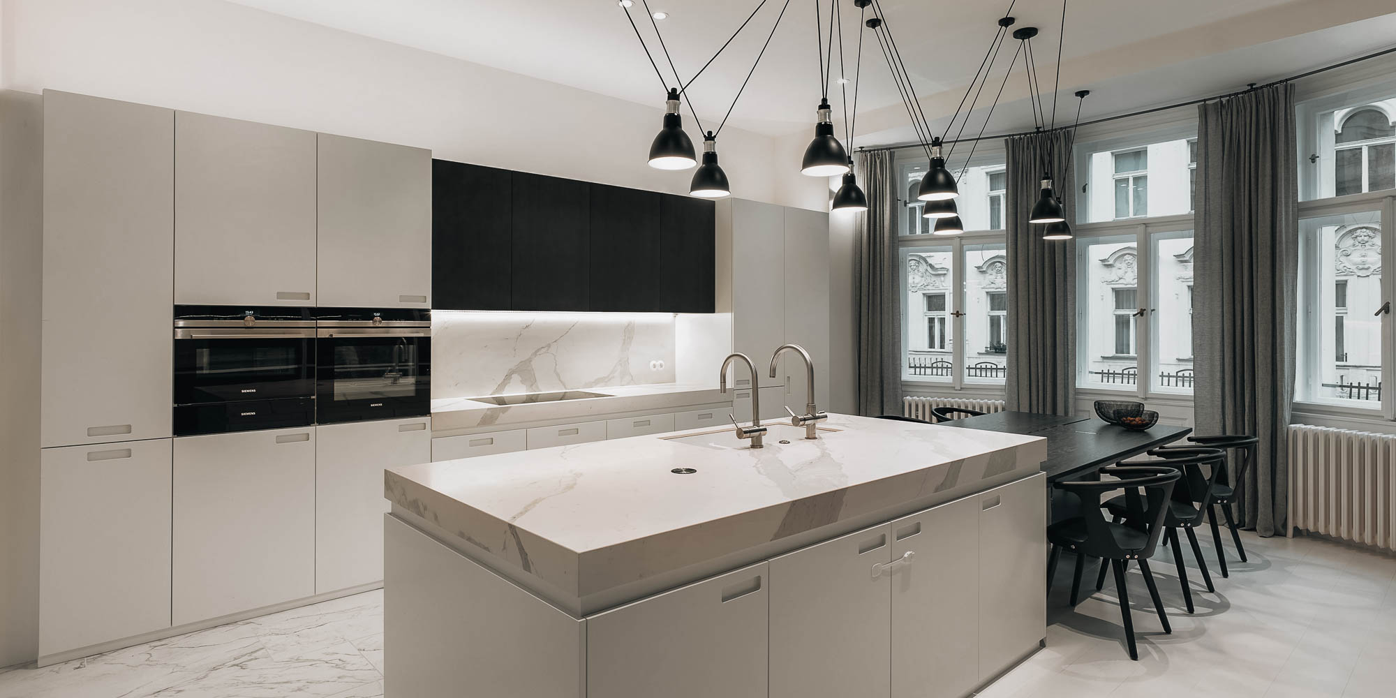 White marble kitchen island black spider pendant lights Prague Old Town baroque facade view French windows OOOOX
