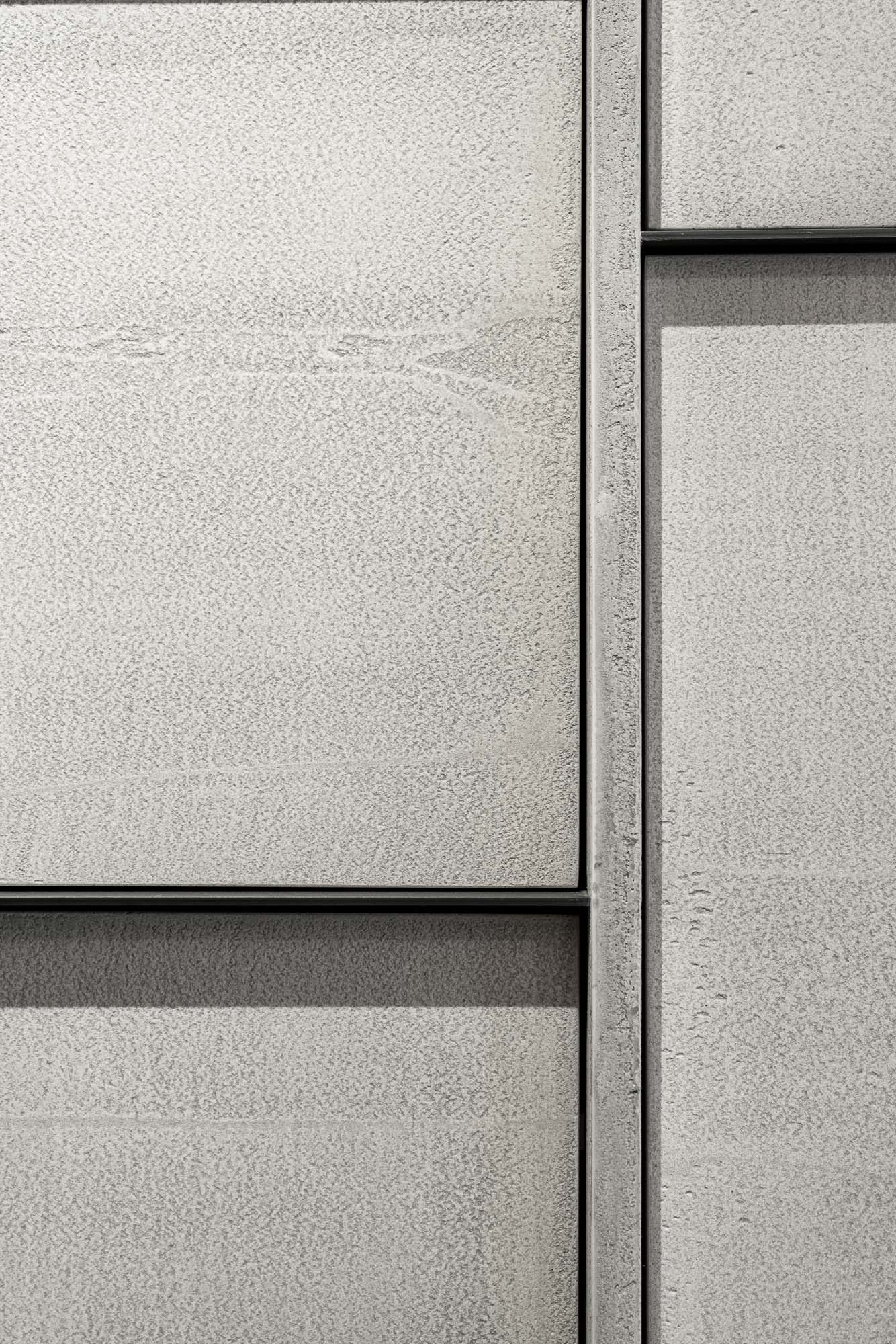 Detail of the shelving cabinet system at Selection Properties — light plaster-finished panels at varying depths and layers, dark steel profiles as dividers